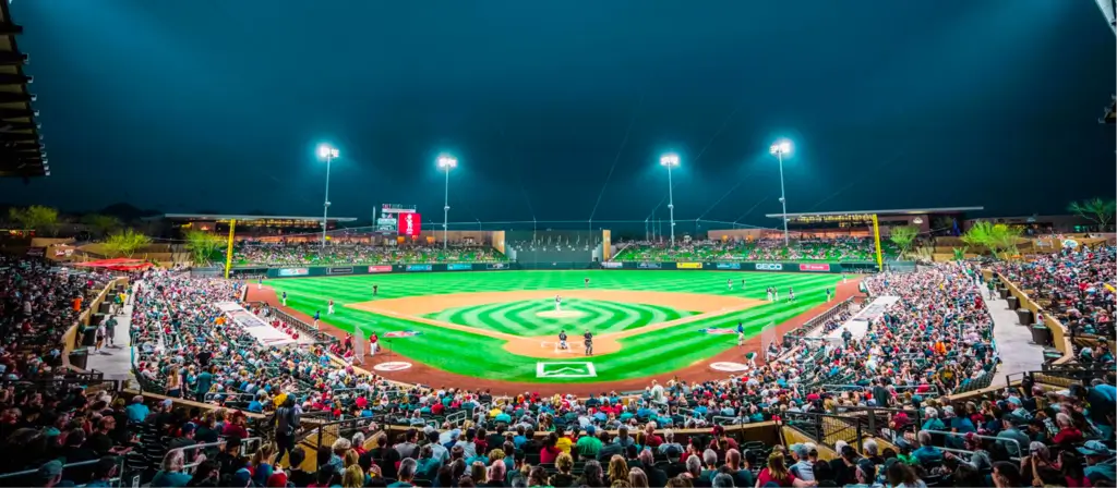 Packed baseball stadium at night with bright lights and vibrant green field